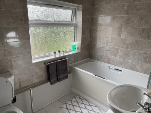 a bathroom with a tub and a sink and a window at Silver Stag Properties,Comfy House in Coalville in Hugglescote