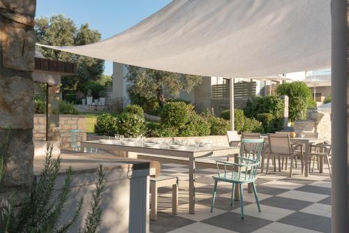 a patio with tables and chairs under a white canopy at Eco Villa, a perfect escape close to the beach, By ThinkVilla in Maroulás