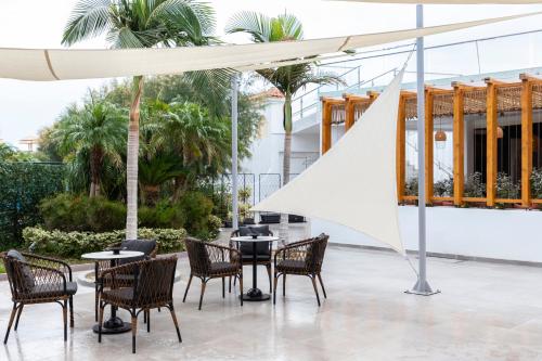 a group of tables and chairs under a white umbrella at Eden Roc Resort - All Inclusive in Kallithea Rhodes