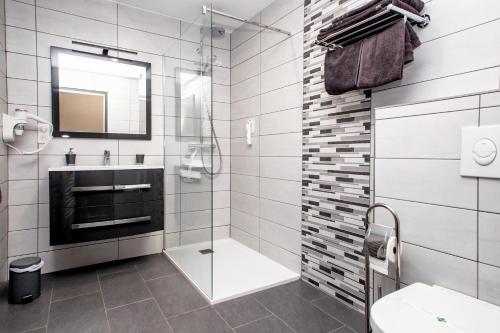 a bathroom with a glass shower and a sink at The Originals Boutique, Hôtel La Baie de Morlaix in Carantec