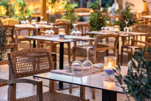 a restaurant with tables and chairs with glasses and candles at Eden Roc Resort - All Inclusive in Kallithea Rhodes