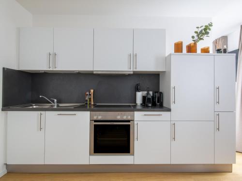 a kitchen with white cabinets and a sink at limehome Passau Bahnhofstraße in Passau