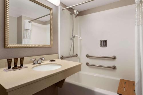 a bathroom with a sink and a tub and a mirror at Wingate by Wyndham Bridgeport Clarksburg in Bridgeport