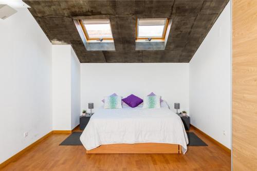 a bedroom with a bed and two windows at Bocage Loft (Setúbal downtown) in Setúbal