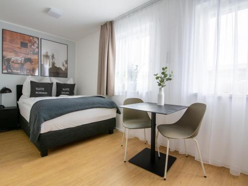 a bedroom with a bed and a table with chairs at Limehome Passau Bahnhofstraße in Passau