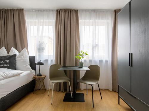 a bedroom with a bed and a table and chairs at Limehome Passau Bahnhofstraße in Passau