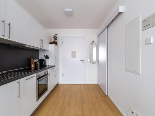 a kitchen with white cabinets and a wooden floor at Limehome Passau Bahnhofstraße in Passau