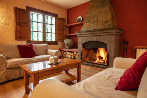 a living room with a fireplace with couches and a table at El Xalet del Priorat in Escaladei