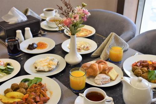 a table topped with plates of breakfast foods and orange juice at Midan Hotel & Suites Al Aziziya in Makkah