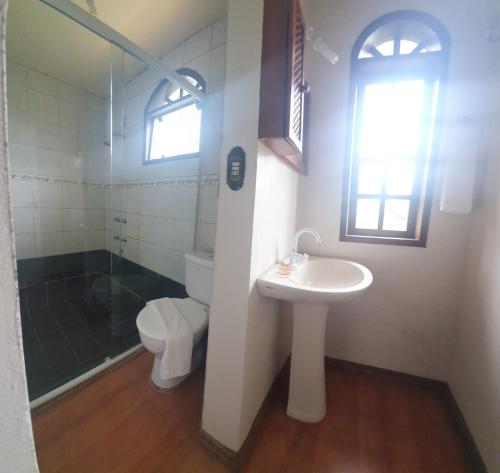 a bathroom with a sink and a toilet and a window at Hotel Ferrugem Eco Village in Garopaba