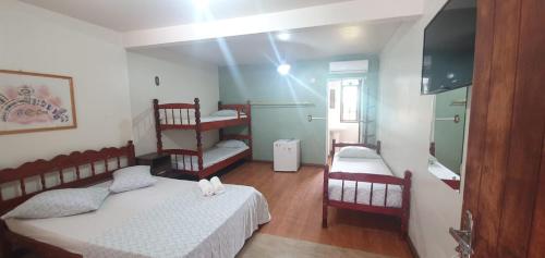 a small room with two beds and a television at Hotel Ferrugem Eco Village in Garopaba