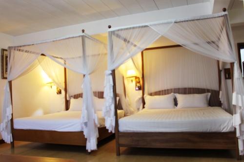 two beds in a bedroom with white drapes at Sunny Garden in Antananarivo