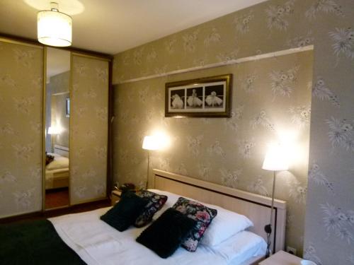 een slaapkamer met een bed met 2 lampen en een spiegel bij Apartament BB II z ogródkiem in Krynica Zdrój