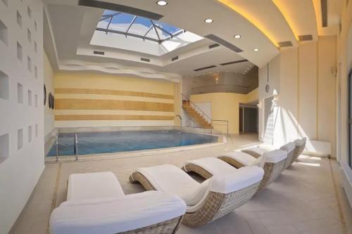 a large swimming pool with white chairs in a room at Delina Mountain Resort in Anogia