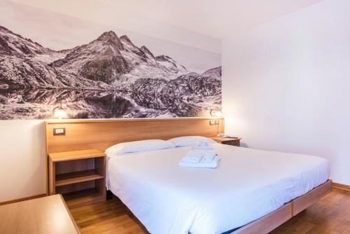 ein Hotelzimmer mit einem Bett mit einem Wandbild der Berge in der Unterkunft Residence Park Imperator Quadri in Carisolo