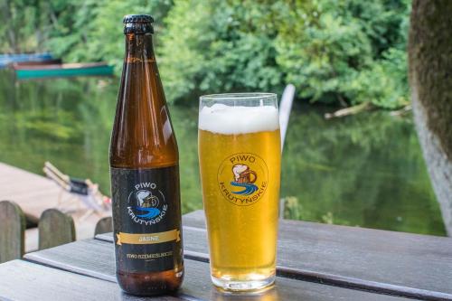 a bottle of beer sitting on a table next to a glass at Kompleks Wypoczynkowo-Konferencyjny Mazur-Syrenka in Krutyń