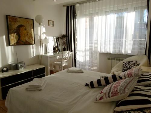 1 dormitorio con 1 cama blanca con silla y ventana en Apartament BB Źródlana, en Krynica-Zdrój