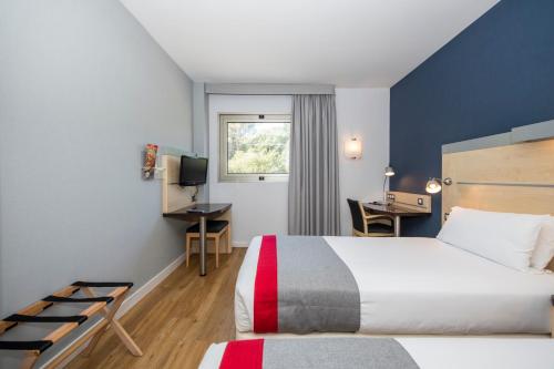 グラノリェースにあるHoliday Inn Express Barcelona - Montmeló, an IHG Hotelのベッドとデスクが備わるホテルルームです。