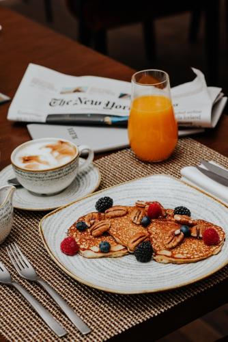 a table with two plates of pancakes and a glass of orange juice at BLESS Hotel Madrid - The Leading Hotels of the World in Madrid