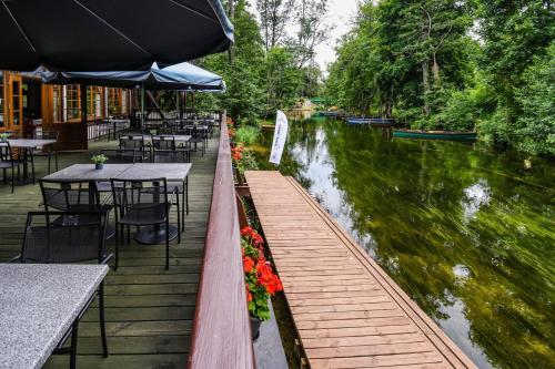 a restaurant with tables and chairs next to a river at Kompleks Wypoczynkowo-Konferencyjny Mazur-Syrenka in Krutyń