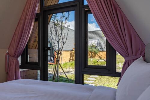 una camera da letto con un letto e una grande finestra di vetro di 花蓮晨風星語民宿Sun Star B&B a Ji'an