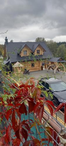 a house with a car parked in front of it at Domek Nad River San - pierwsza linia brzegowa - balia - łodzie - basen in Olchowiec