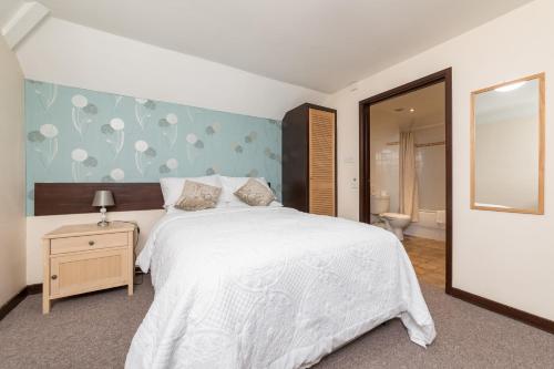 ein Schlafzimmer mit einem großen weißen Bett und einem Spiegel in der Unterkunft The Black Horse in Swaffham Bulbeck