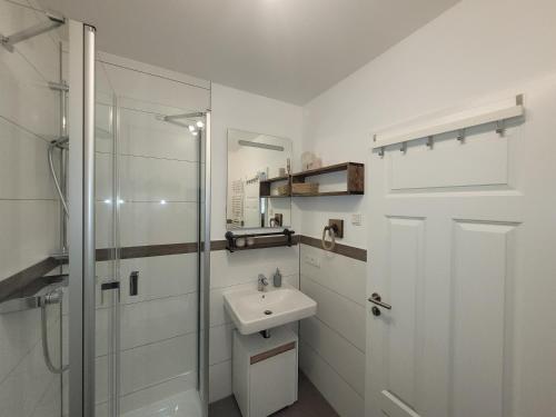 a white bathroom with a sink and a shower at Sonneninsel & Ankerplatz Wiek in Wiek auf Rügen 