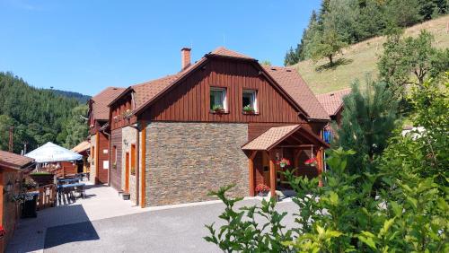 a large building with a stone wall next to a mountain at U Veselé lišky in Hutisko