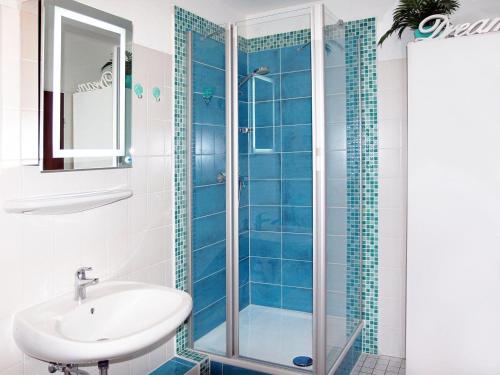 een badkamer met een wastafel en een douche met blauwe tegels bij STR-101-Strandallee-124-Seeblick in Scharbeutz