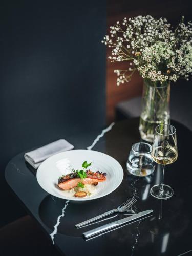 a plate of food on a table with a vase of flowers at Hôtel LÉONOR the place to live in Strasbourg