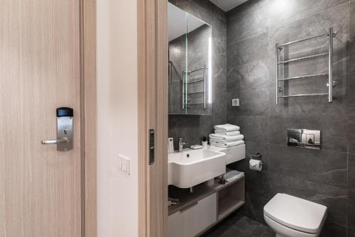 La salle de bains est pourvue d'un lavabo blanc et de toilettes. dans l'établissement Apart-hotel YE'S Botanica, à Moscou