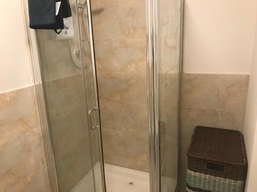 a shower with a glass door with a stool at Central town location apartment in Enniscorthy