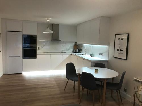 uma cozinha com mesa e cadeiras e uma cozinha com armários brancos em Central town location apartment em Enniscorthy