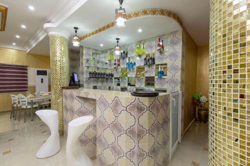 a kitchen with a bar with two white stools at Amazing Grace Hotel & Suites in Accra