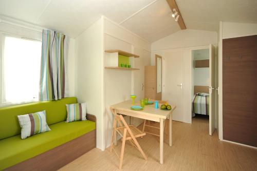 Cette petite chambre comprend un canapé vert et une table. dans l'établissement Camping Les Albères - Maeva, à Laroque-des-Albères