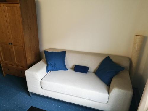 a white couch with two blue pillows on it at Casa Koraal - Old Town Zug in Zug