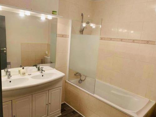 La salle de bains est pourvue d'un lavabo, d'une douche et d'une baignoire. dans l'établissement Ravissant Appartement T3 hypercentre de Mazamet, à Mazamet