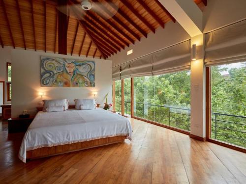 a bedroom with a large bed and large windows at The Glasshouse Victoria Villa, Kandy in Digana