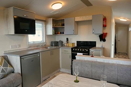 a small kitchen with a stove and a couch at Plot 8 Lakeside Cabin, Wyldecrest, Millom in Millom