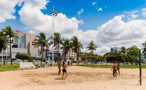 a group of people playing a game of volleyball on a beach at ibis Vitoria Praia de Camburi in Vitória