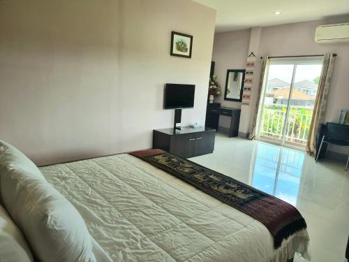 a bedroom with a bed and a tv and a window at Chiangkham Grand Villa - SHA Certified in Chiang Kham