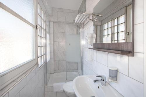 a white bathroom with a sink and a toilet at Relax Hotel & SPA Stuttgart in Stuttgart