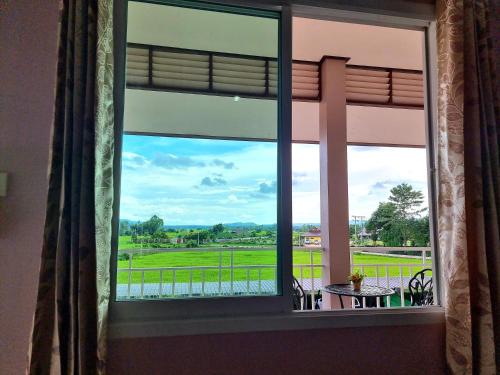 a window with a view of a green field at Chiangkham Grand Villa - SHA Certified in Chiang Kham