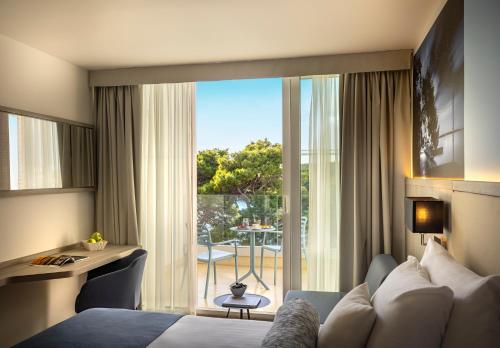a hotel room with a bed and a large window at Valamar Carolina Hotel & Villas in Rab