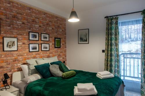 um quarto com uma cama verde e uma parede de tijolos em Szczyrkowskie SKI & FUN 16 - z widokiem na góry em Szczyrk