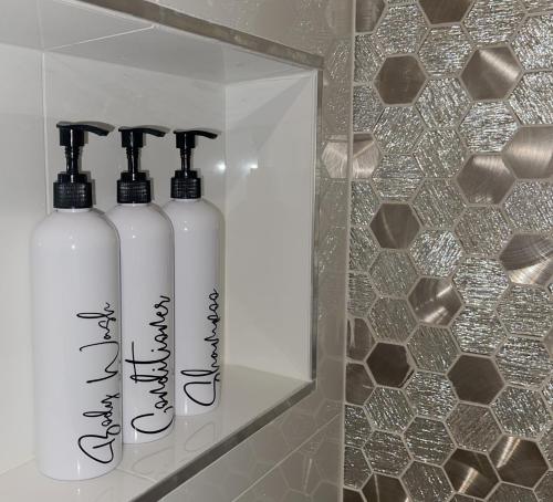 two white bottles sitting on a shelf in a bathroom at Park Plaza Lodge in Los Angeles