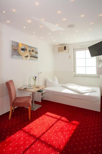 a bedroom with a bed and a desk and a red rug at Relax Hotel & SPA Stuttgart in Stuttgart