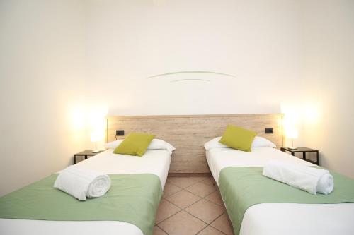 two beds with green and white pillows in a room at Hotel Tornielli 9 by LVG Hotel Collection in Novara
