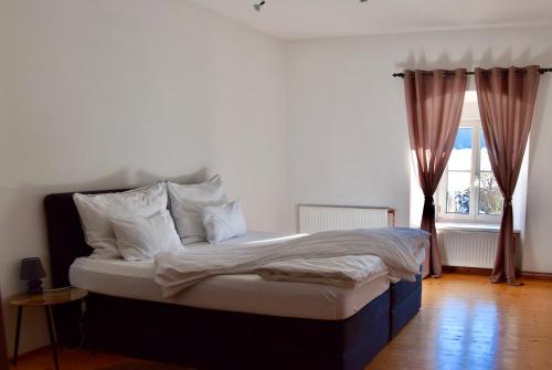a bed with white sheets and pillows in a room with a window at Golf-Appartement in Gleisdorf